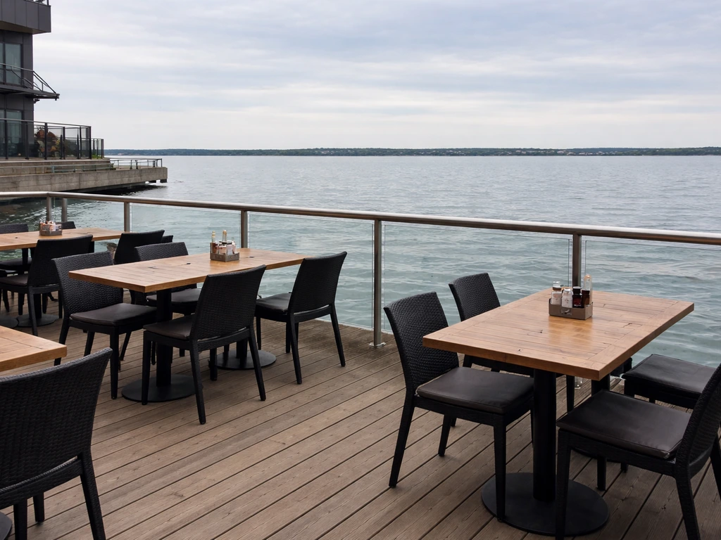 Empty waterfront patio seating with a clear view across Lake Ontario from Toronto.